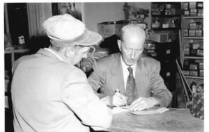 Harry George Sr. writing a check to a customer.png